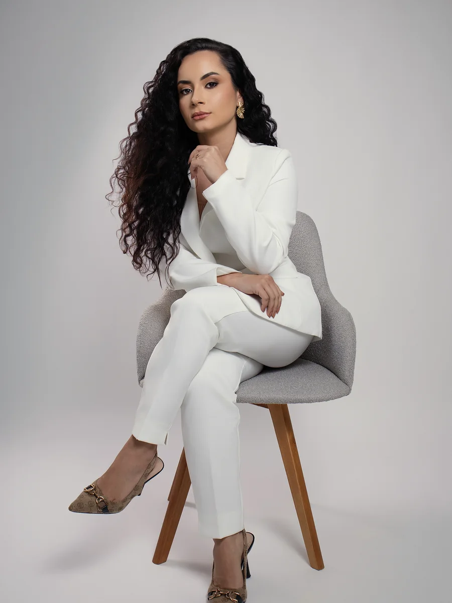 Dra. Gabriella Rodrigues Vieira sentada, em terno branco, no escritório em Linhares/ES